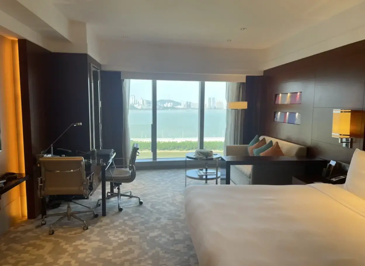 the bed, desk, lounge and view from the window in a deluxe king room at Macau's Crowne Plaza hotel